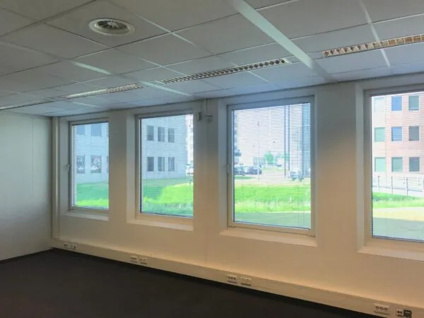 Leeg kantoorruimte met systeemplafond en grote ramen met uitzicht op kantoorpanden aan het Rivium Quadrant.